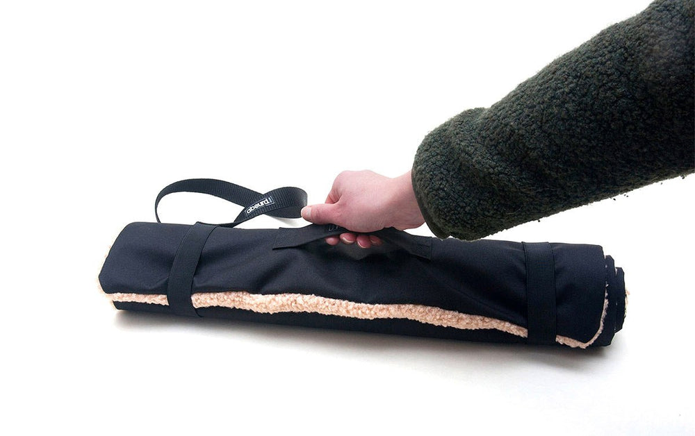 hand coming into the picture to pick up the Travel Mat by its handle