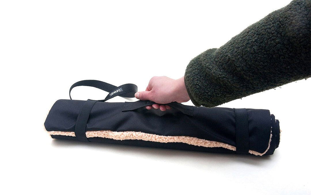 hand coming into the picture to pick up the Travel Mat by its handle