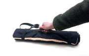 hand coming into the picture to pick up the Travel Mat by its handle